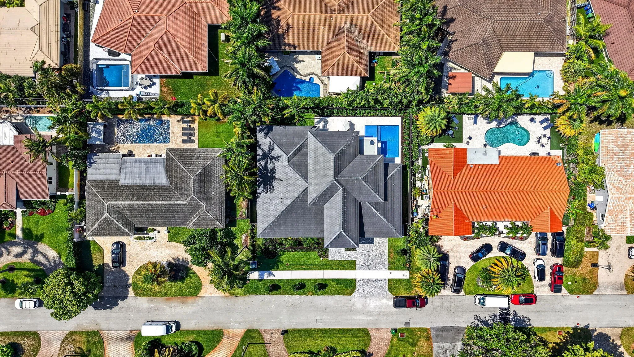 Elevated photography showcases the home's setting, surrounding luxury residences, and proximity to South Florida lifestyle destinations.
