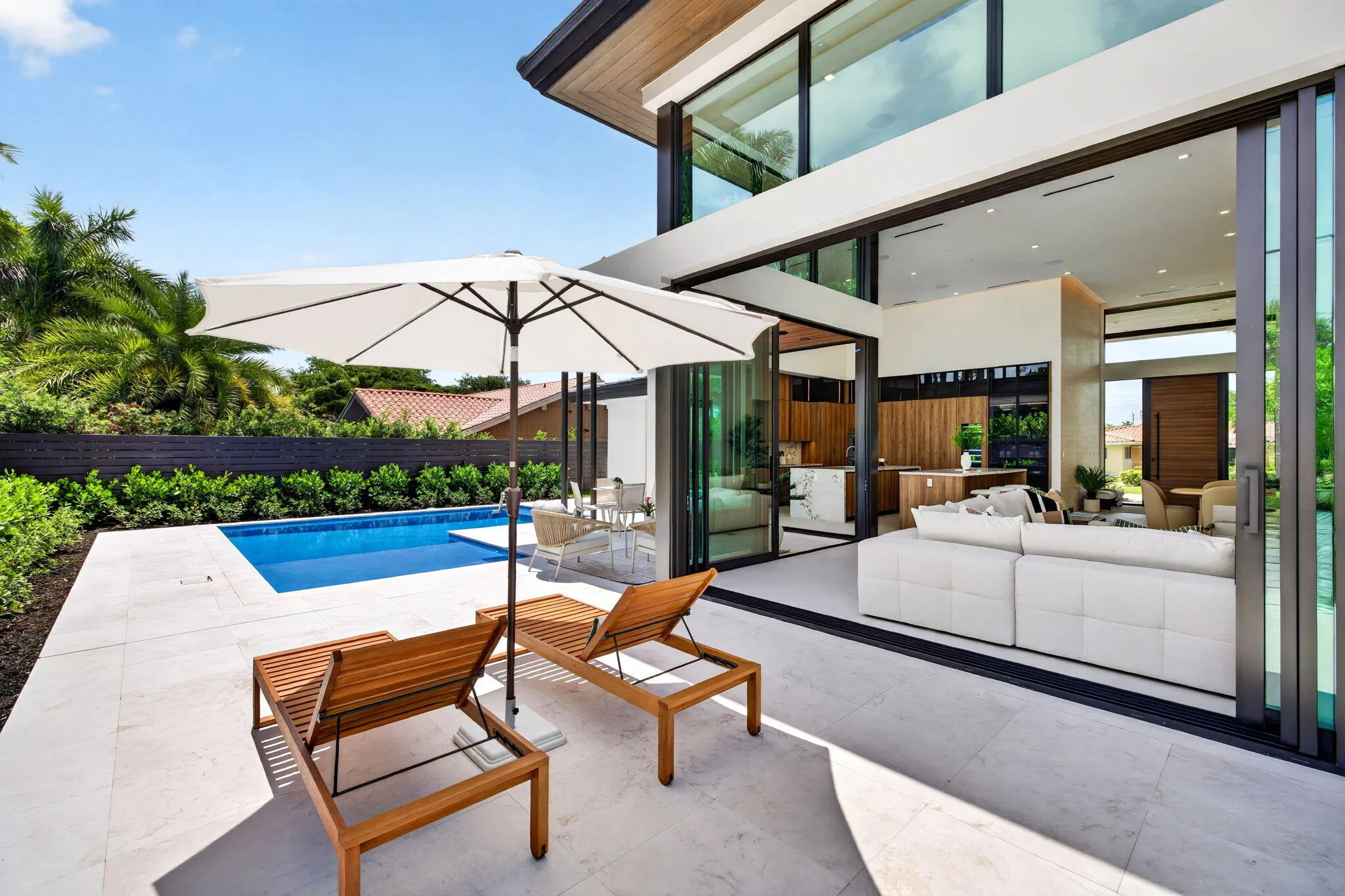 A resort-style patio setting connects the interiors to the pool, landscaping, and year-round open-air living.