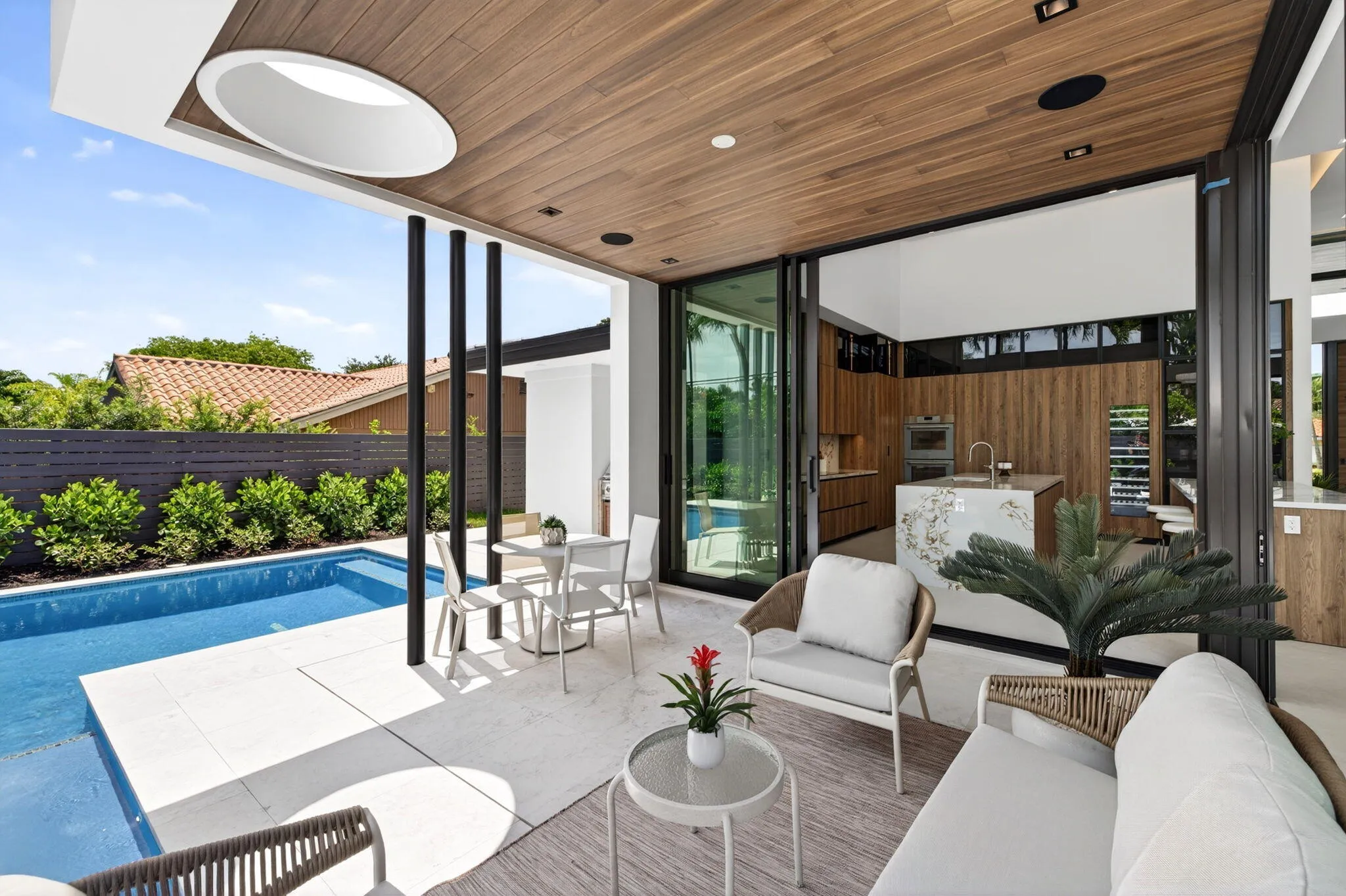 Covered outdoor living extends the residence to the private pool, summer kitchen, and fully fenced tropical grounds.