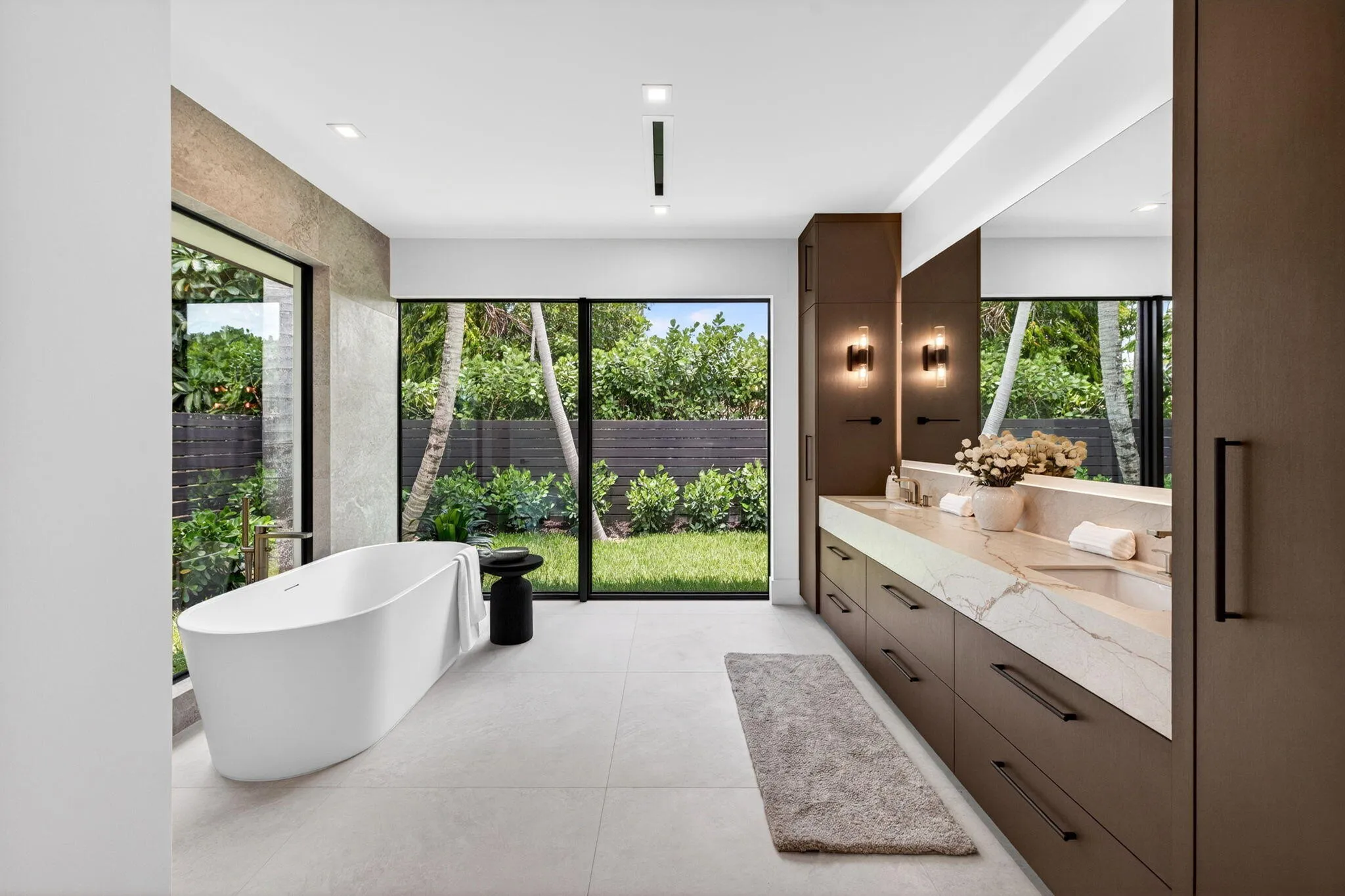 Spa-inspired bath finishes create a quiet luxury experience with sleek vanities, glass, stone, and tranquil garden outlooks.