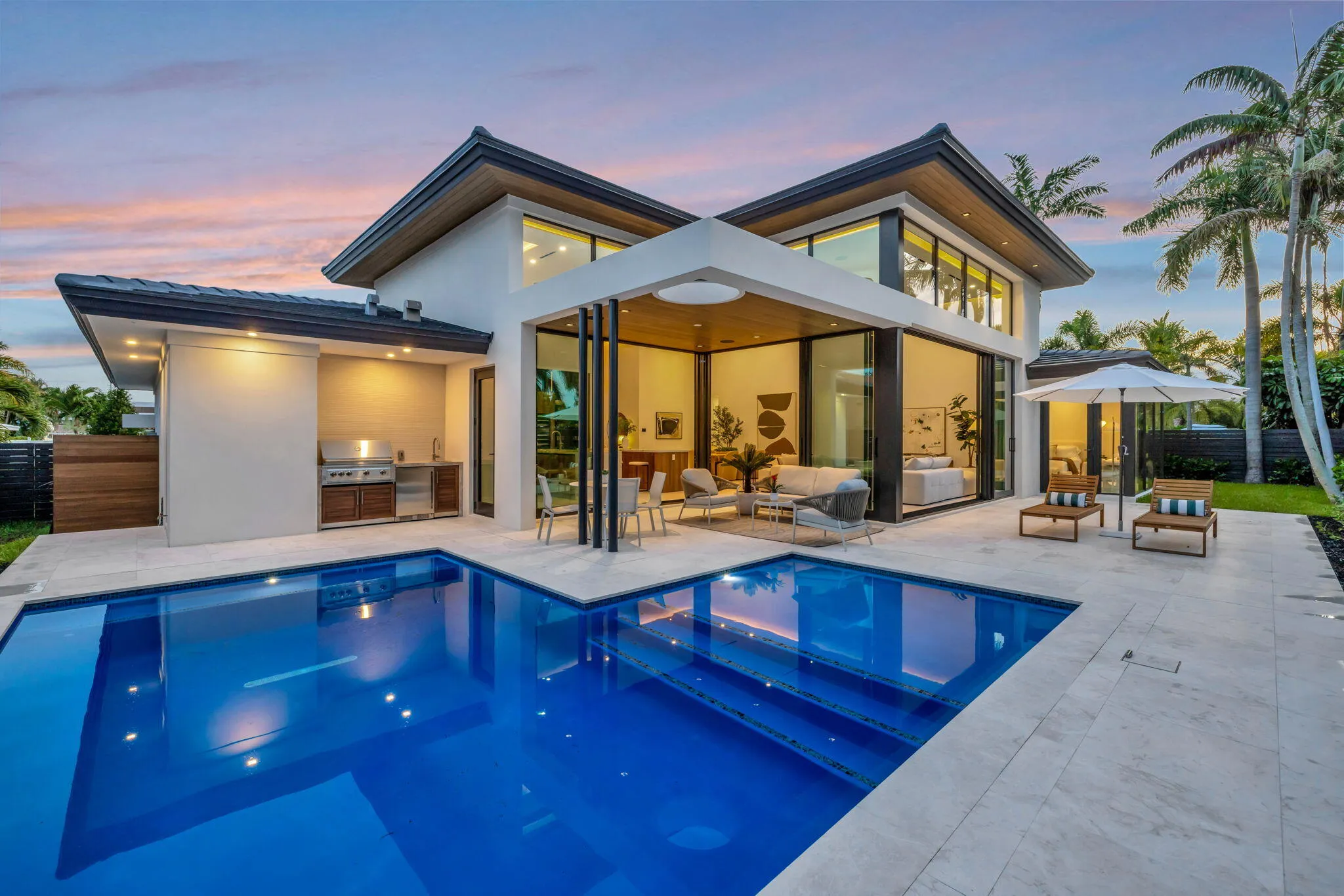 A resort-style patio setting connects the interiors to the pool, landscaping, and year-round open-air living.