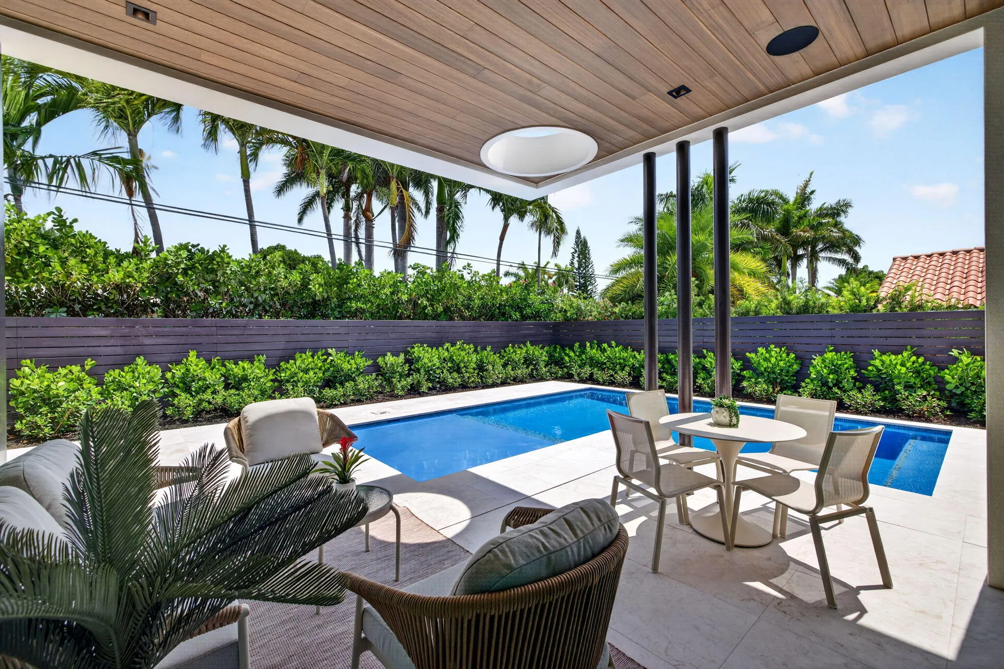 The outdoor living areas are designed for relaxed South Florida entertaining with shaded seating, pool views, and privacy.