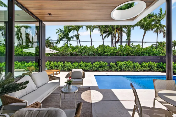 A resort-style patio setting connects the interiors to the pool, landscaping, and year-round open-air living.