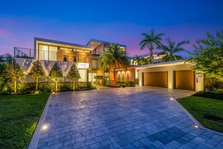 A polished arrival moment showcasing the estate’s contemporary architecture, private gated setting, tropical landscaping, and impressive motor court presence.