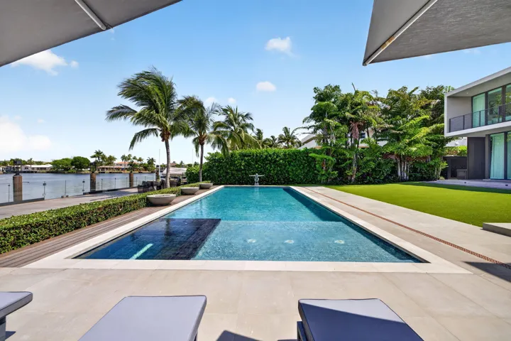A resort-inspired waterfront setting showcasing the 50-foot saltwater pool, manicured grounds, and striking contemporary rear elevation.
