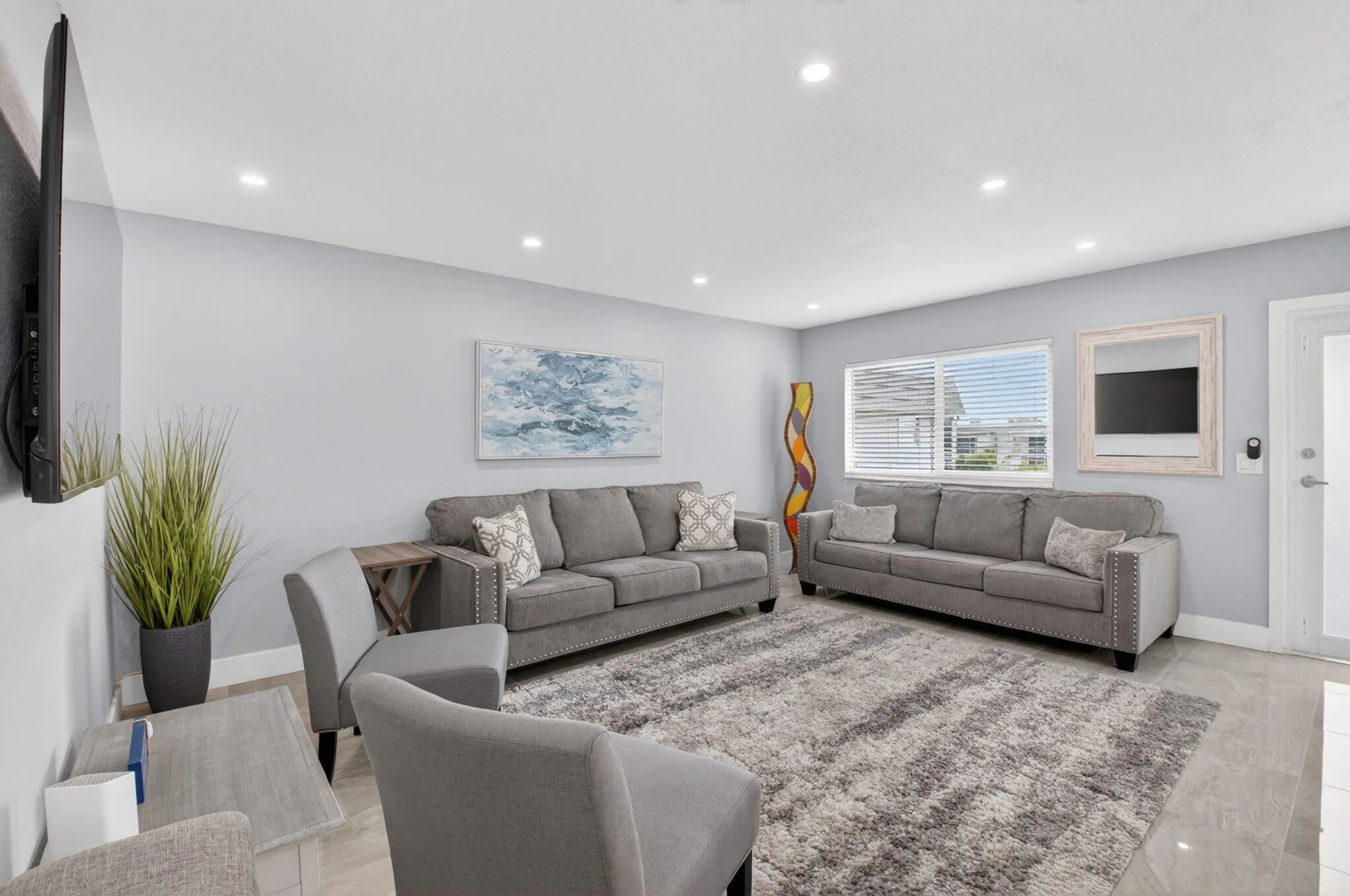 Modern designed living room with large flat screen tv makes this space perfect for movie night! (One couch will be removed prior to move-in)