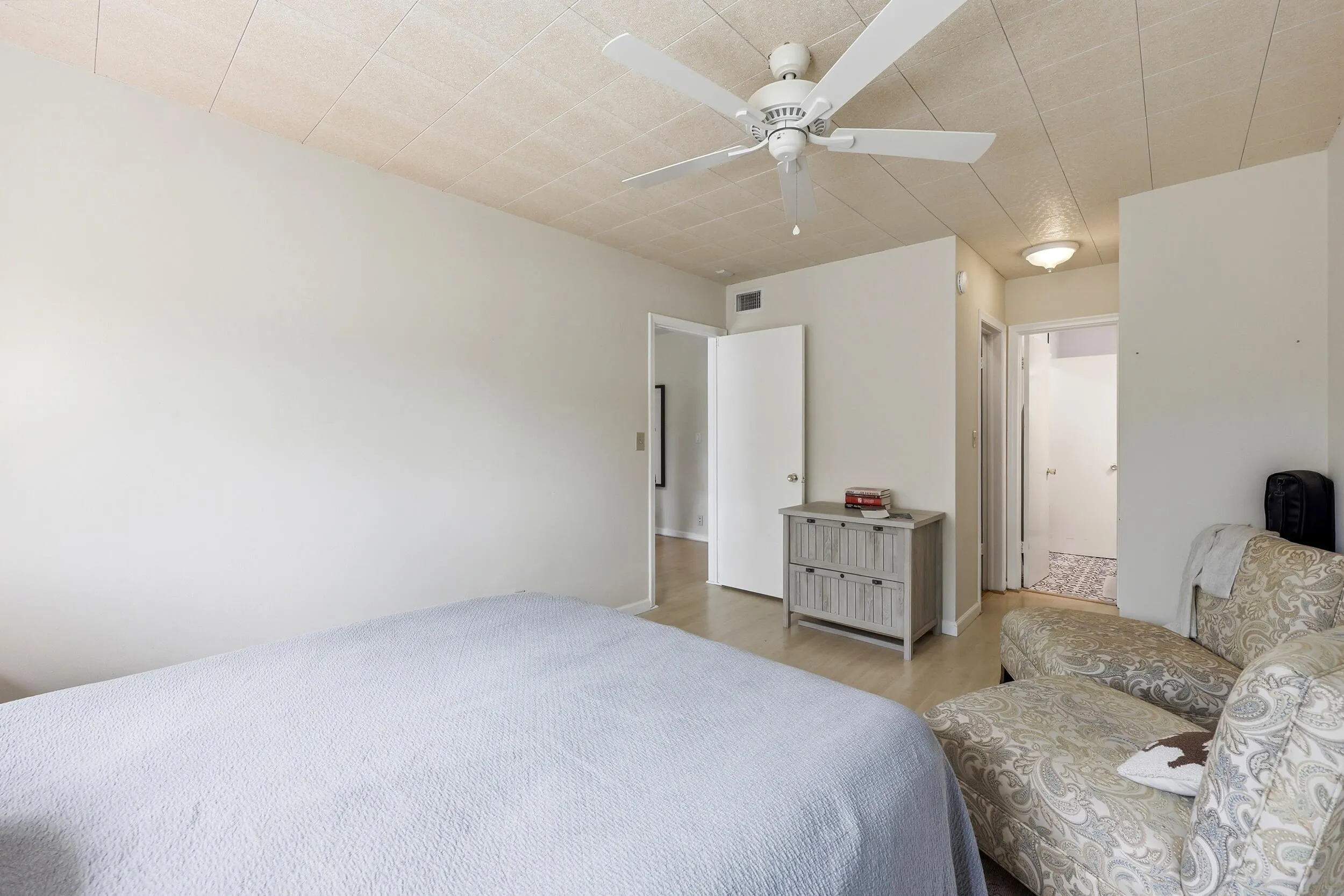 The generously sized primary bedroom offers a peaceful retreat with ample space for a king-sized bed and additional furnishings. Large windows invite natural light while showcasing tranquil treetop views that enhance the room's relaxing atmosphere. Neutral finishes and wood-look flooring create a bright, airy feel, while the spacious layout provides flexibility for a sitting area, home office nook, or additional storage. Convenient access to the bathroom and generous closet space complete this comfortable and functional owner's suite.