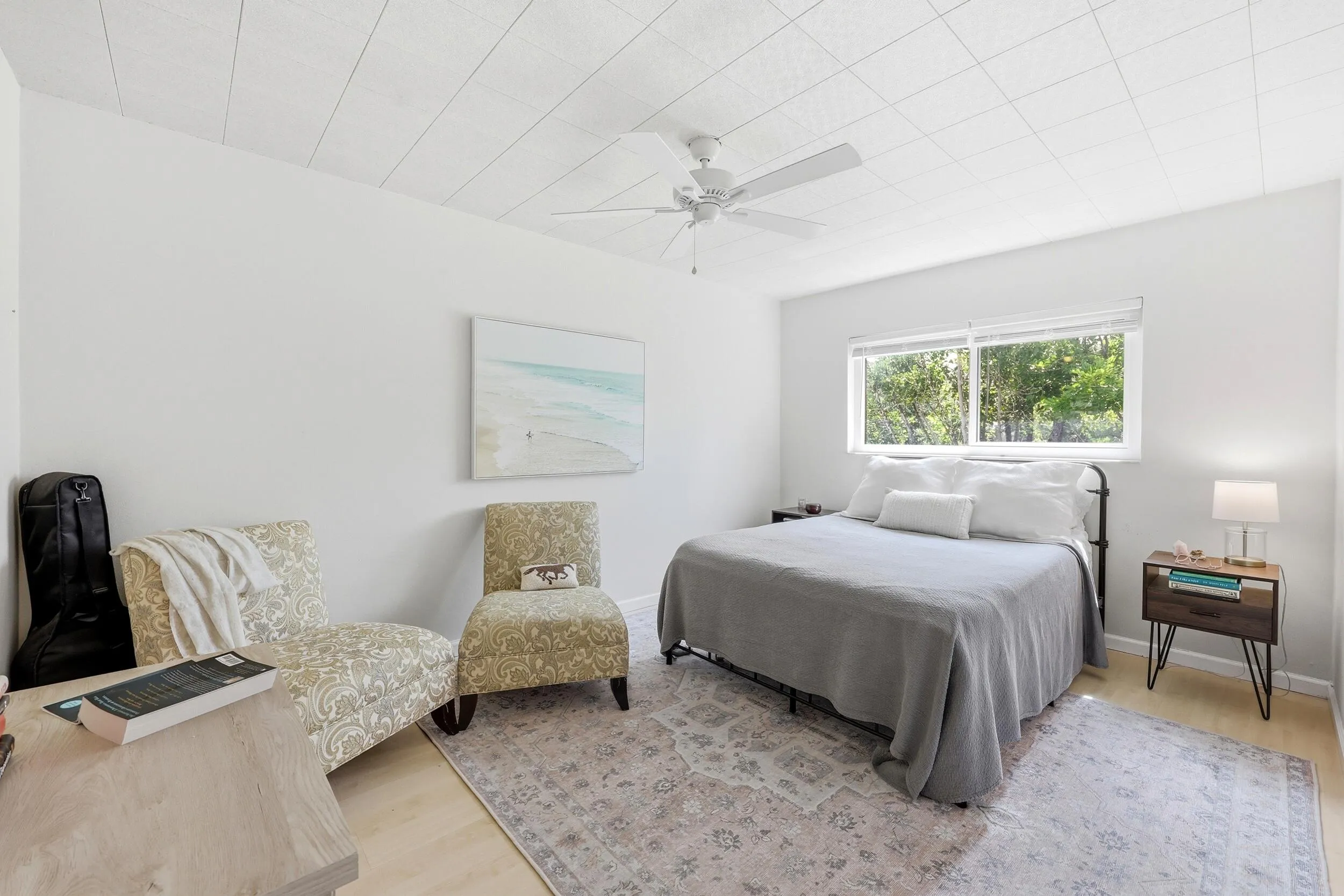 The generously sized primary bedroom offers a peaceful retreat with ample space for a king-sized bed and additional furnishings. Large windows invite natural light while showcasing tranquil treetop views that enhance the room's relaxing atmosphere. Neutral finishes and wood-look flooring create a bright, airy feel, while the spacious layout provides flexibility for a sitting area, home office nook, or additional storage. Convenient access to the bathroom and generous closet space complete this comfortable and functional owner's suite.