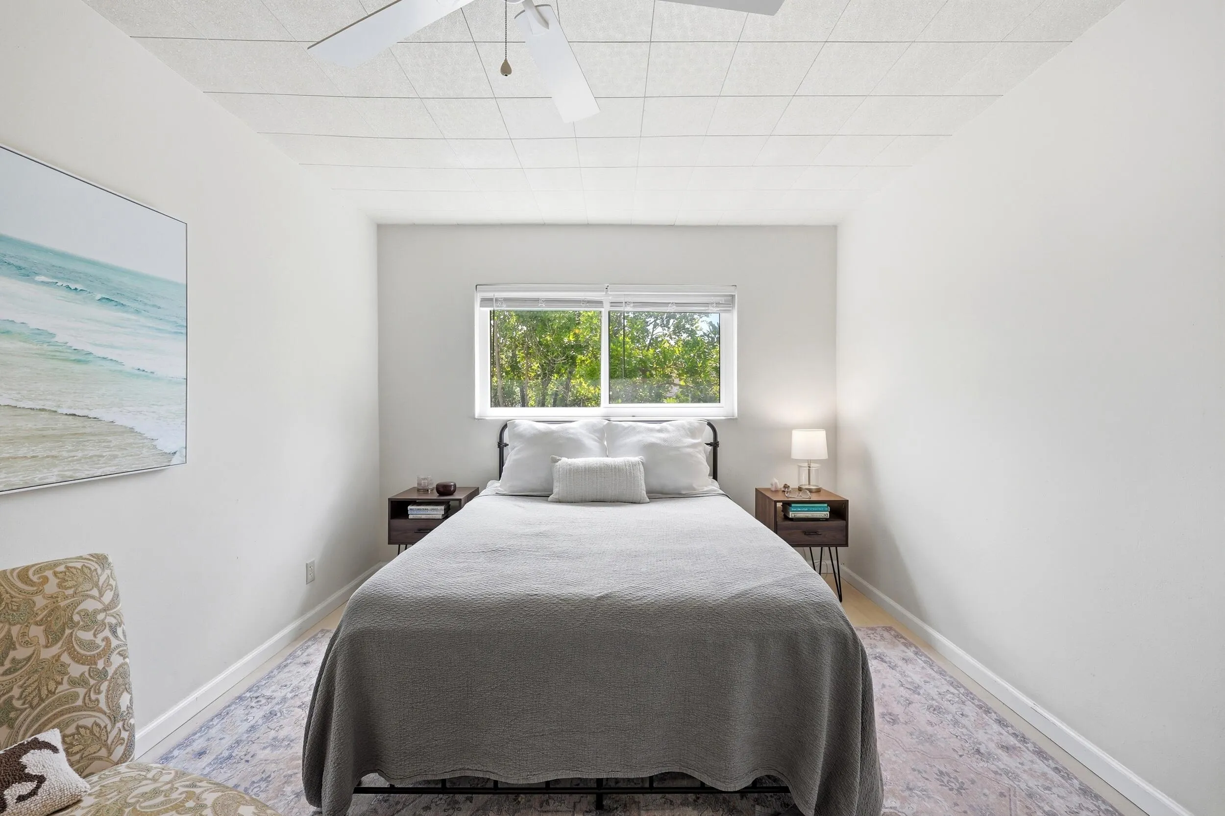 The generously sized primary bedroom offers a peaceful retreat with ample space for a king-sized bed and additional furnishings. Large windows invite natural light while showcasing tranquil treetop views that enhance the room's relaxing atmosphere. Neutral finishes and wood-look flooring create a bright, airy feel, while the spacious layout provides flexibility for a sitting area, home office nook, or additional storage. Convenient access to the bathroom and generous closet space complete this comfortable and functional owner's suite.
