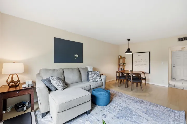 The spacious living room is filled with natural light and offers a comfortable setting for both relaxing and entertaining. Large windows frame peaceful treetop views, creating a bright and inviting atmosphere throughout the day. The open-concept layout flows seamlessly into the dining area, while neutral finishes and wood-look flooring provide a clean, versatile backdrop for any design style. Ample wall space and an efficient floor plan maximize both functionality and comfort, making this the perfect place to unwind or gather with friends and family.