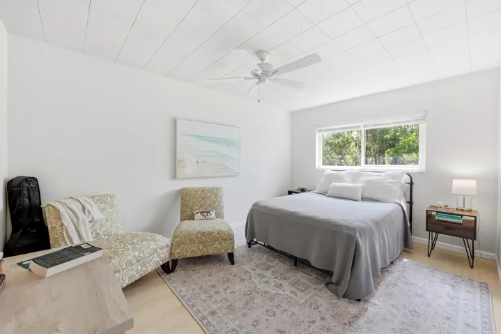 The generously sized primary bedroom offers a peaceful retreat with ample space for a king-sized bed and additional furnishings. Large windows invite natural light while showcasing tranquil treetop views that enhance the room's relaxing atmosphere. Neutral finishes and wood-look flooring create a bright, airy feel, while the spacious layout provides flexibility for a sitting area, home office nook, or additional storage. Convenient access to the bathroom and generous closet space complete this comfortable and functional owner's suite.