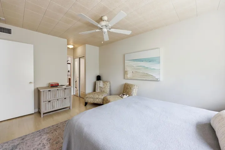 The generously sized primary bedroom offers a peaceful retreat with ample space for a king-sized bed and additional furnishings. Large windows invite natural light while showcasing tranquil treetop views that enhance the room's relaxing atmosphere. Neutral finishes and wood-look flooring create a bright, airy feel, while the spacious layout provides flexibility for a sitting area, home office nook, or additional storage. Convenient access to the bathroom and generous closet space complete this comfortable and functional owner's suite.