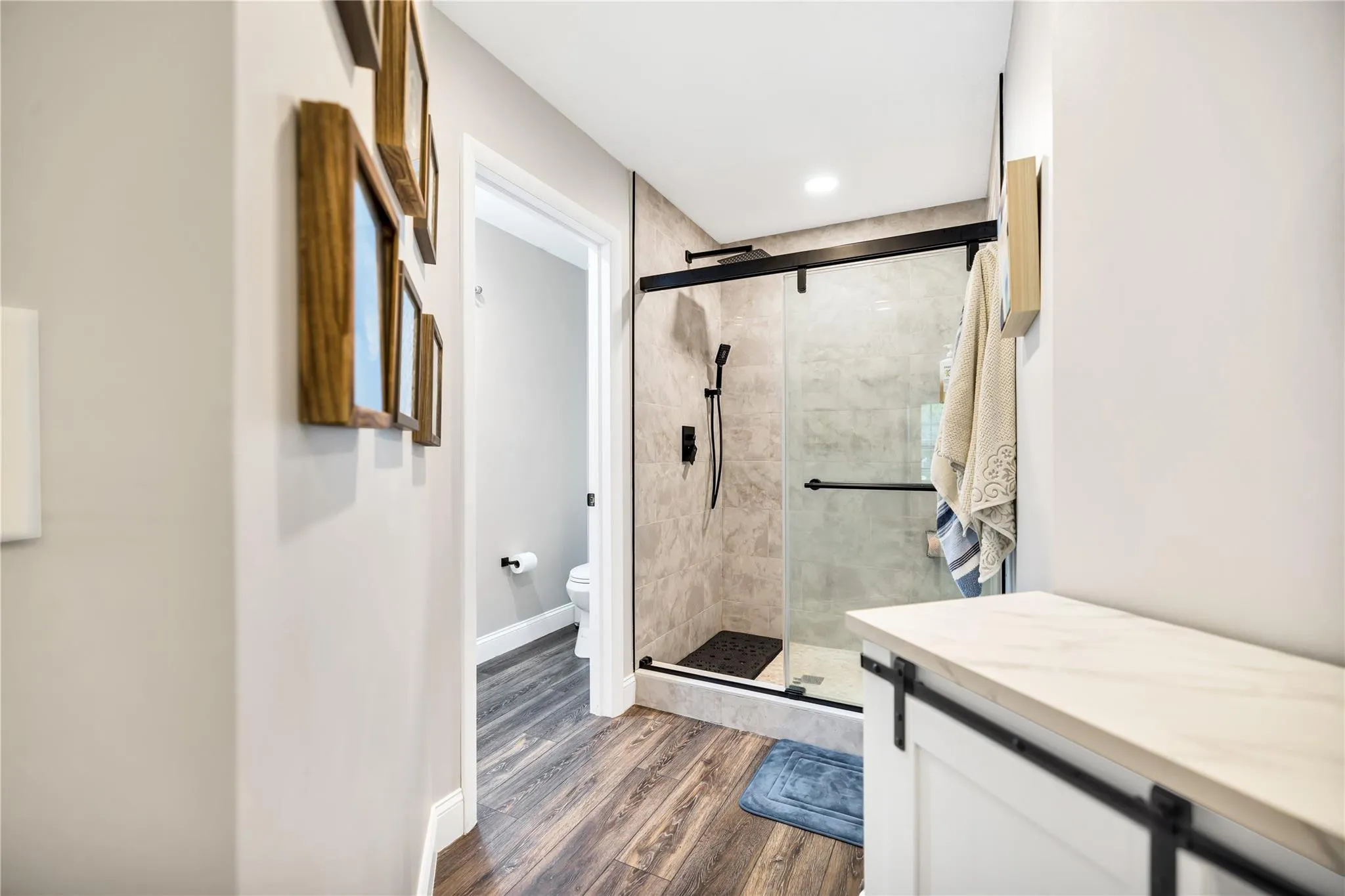 Glass doors for shower, stone mosaic floor and raindown shower head. Private WC with door, to the left.
