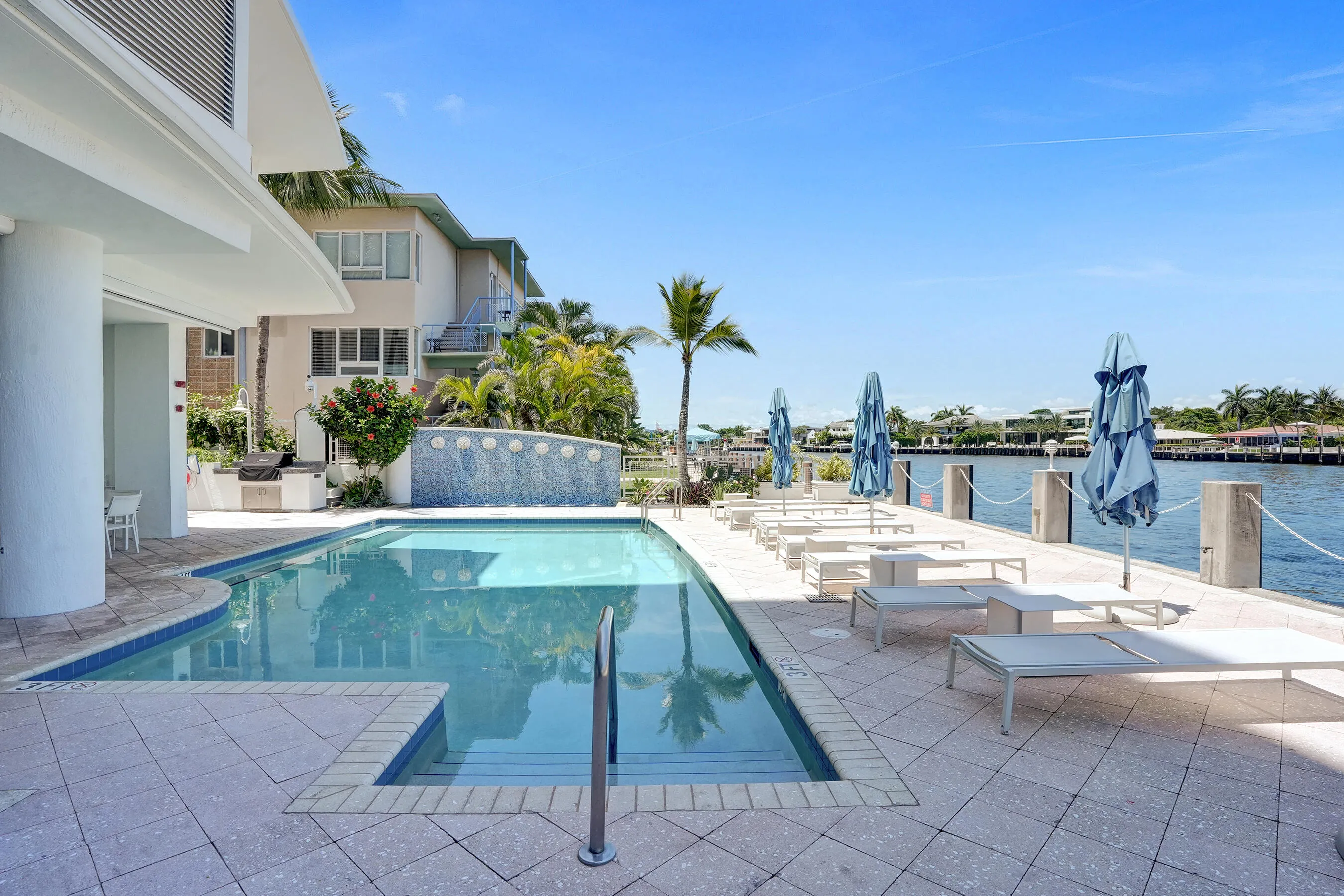 Waterfront Heated Pool along side covered patio, water feature, and built-in BBQ grill