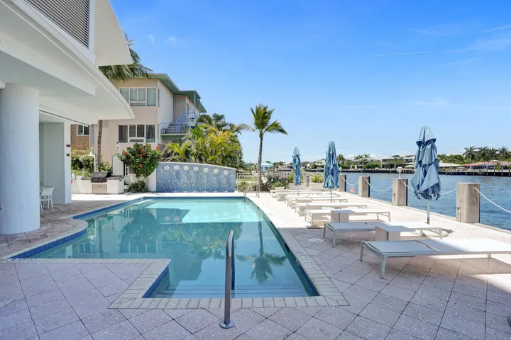 Waterfront Heated Pool along side covered patio, water feature, and built-in BBQ grill