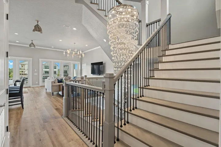 Ascend beneath a breathtaking statement chandelier as this stunning stairwell leads to the private primary retreat and an inviting third-floor guest suite designed for ultimate comfort and luxury.