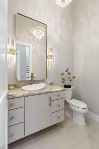 Glamorous lighting, elegant gold accents, and soaring ceilings give this luxurious powder bath a true designer feel that’s guaranteed to impress your guests.