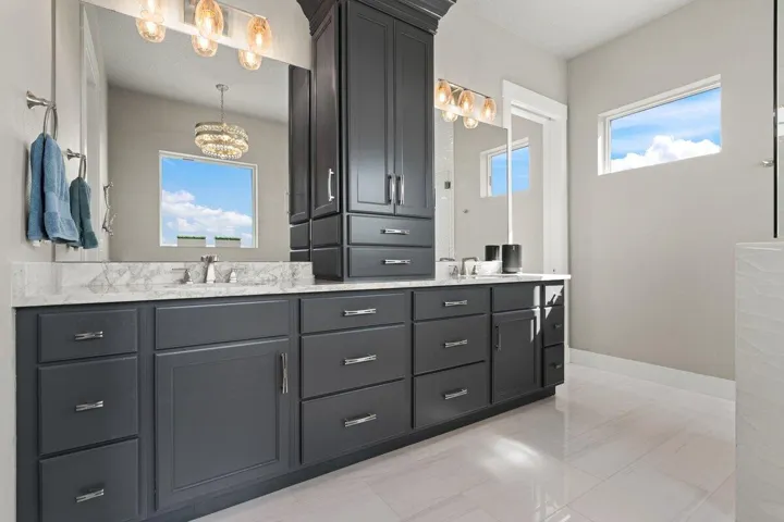 Dual vanities, endless designer storage, and elegant lighting create a glamorous retreat worthy of a luxury waterfront estate.