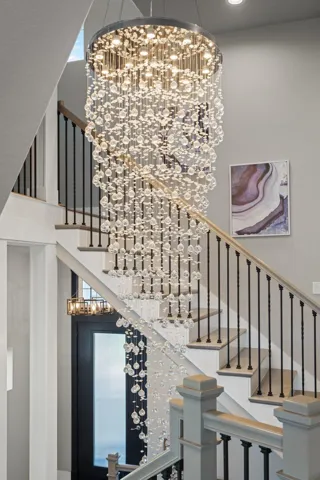 Inside… every detail feels intentional. From the moment you enter, the dramatic chandelier creates a breathtaking focal point, setting the tone for the sophisticated design, soaring ceilings, and expansive open living spaces that unfold beyond.