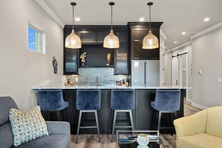Gather around this stunning custom bar where glowing pendant lighting, rich finishes.