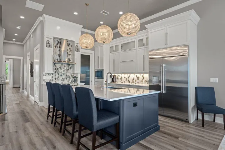 Stunning designer kitchen featuring custom cabinetry, dramatic statement lighting, and an oversized island that naturally becomes the heart of the home.