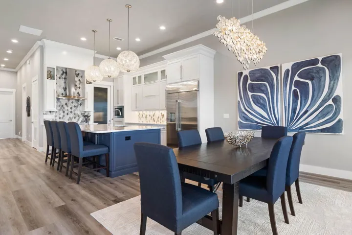 Dramatic designer lighting and bold coastal finishes make this stunning dining and kitchen space feel like the heart of every unforgettable gathering.