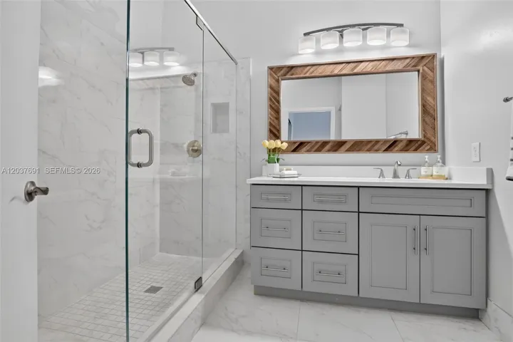 Spa-inspired primary bath features a frameless glass shower, designer vanity and elegant finishes
