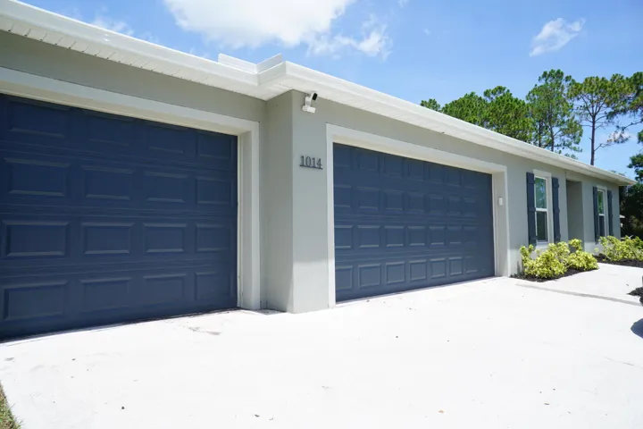 Panel garage doors on a light gray stucco exterior with white trim