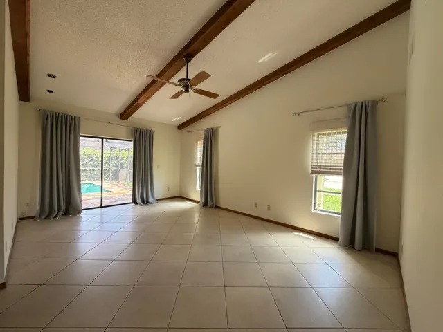 Primary Bedroom with Sliding Glass Doors leading to Screened-in Patio and Pool