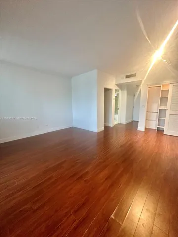 Wood-finish flooring, neutral walls, and built-in closet cabinetry featuring shelving