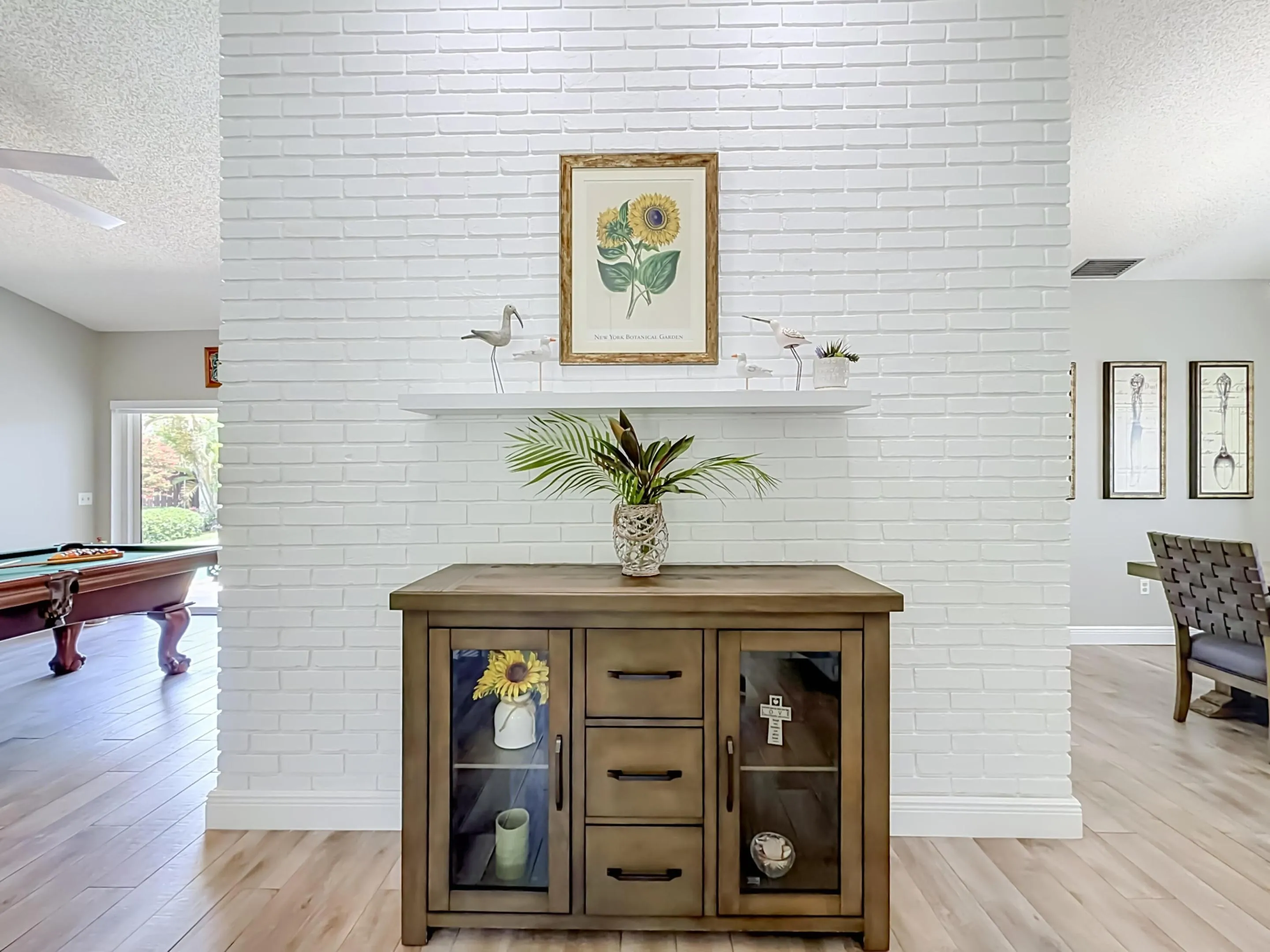 Entrance to Foyer, white brick wall flow to either room, vaulted ceiling, tilled throughout