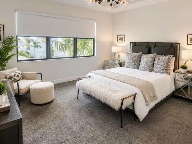 Spacious primary suite filled with natural light and accented by a coffered ceiling.