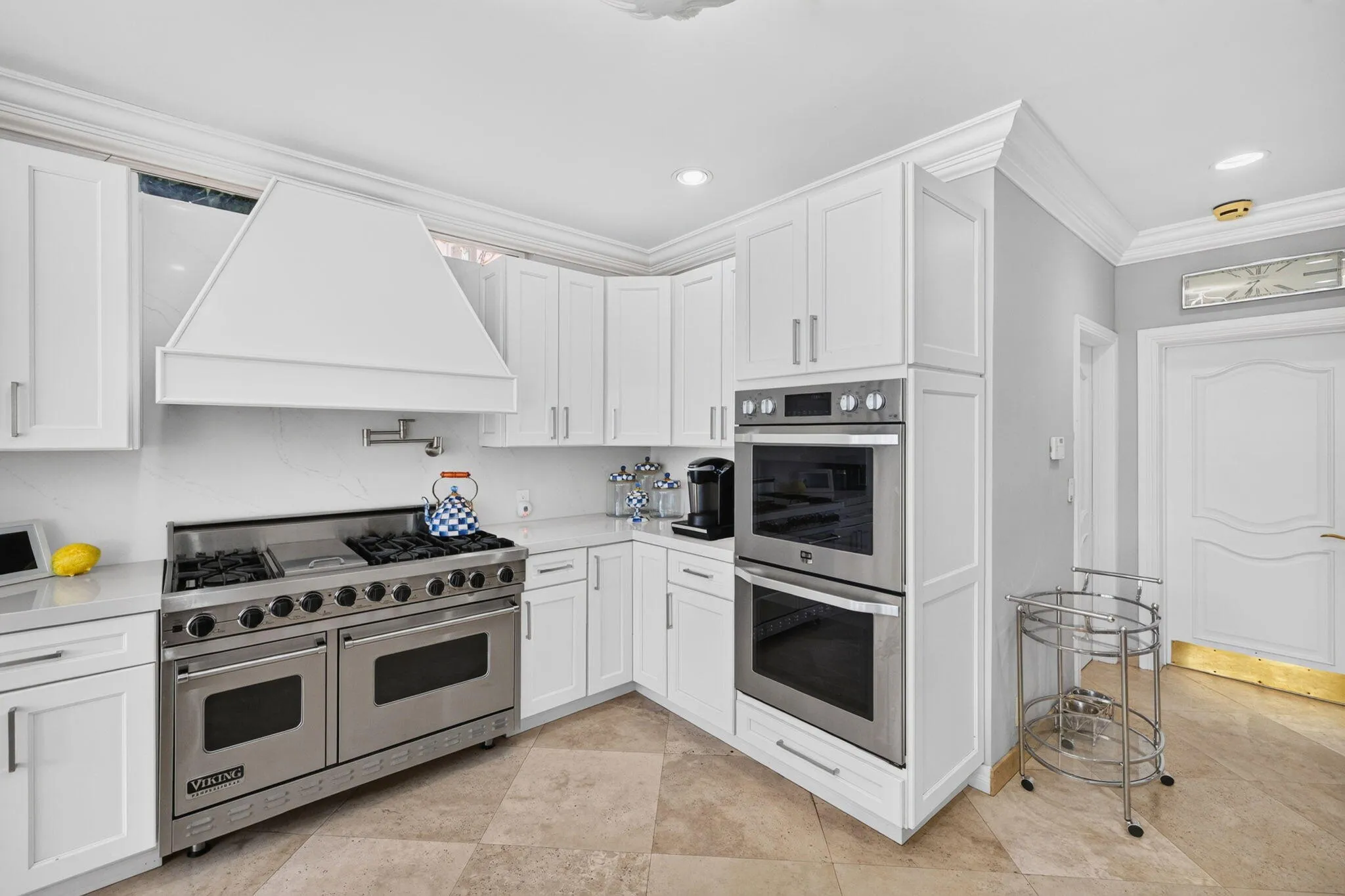 The kitchen’s range wall and built-in appliances provide a crisp, organized workspace for cooking and hosting.