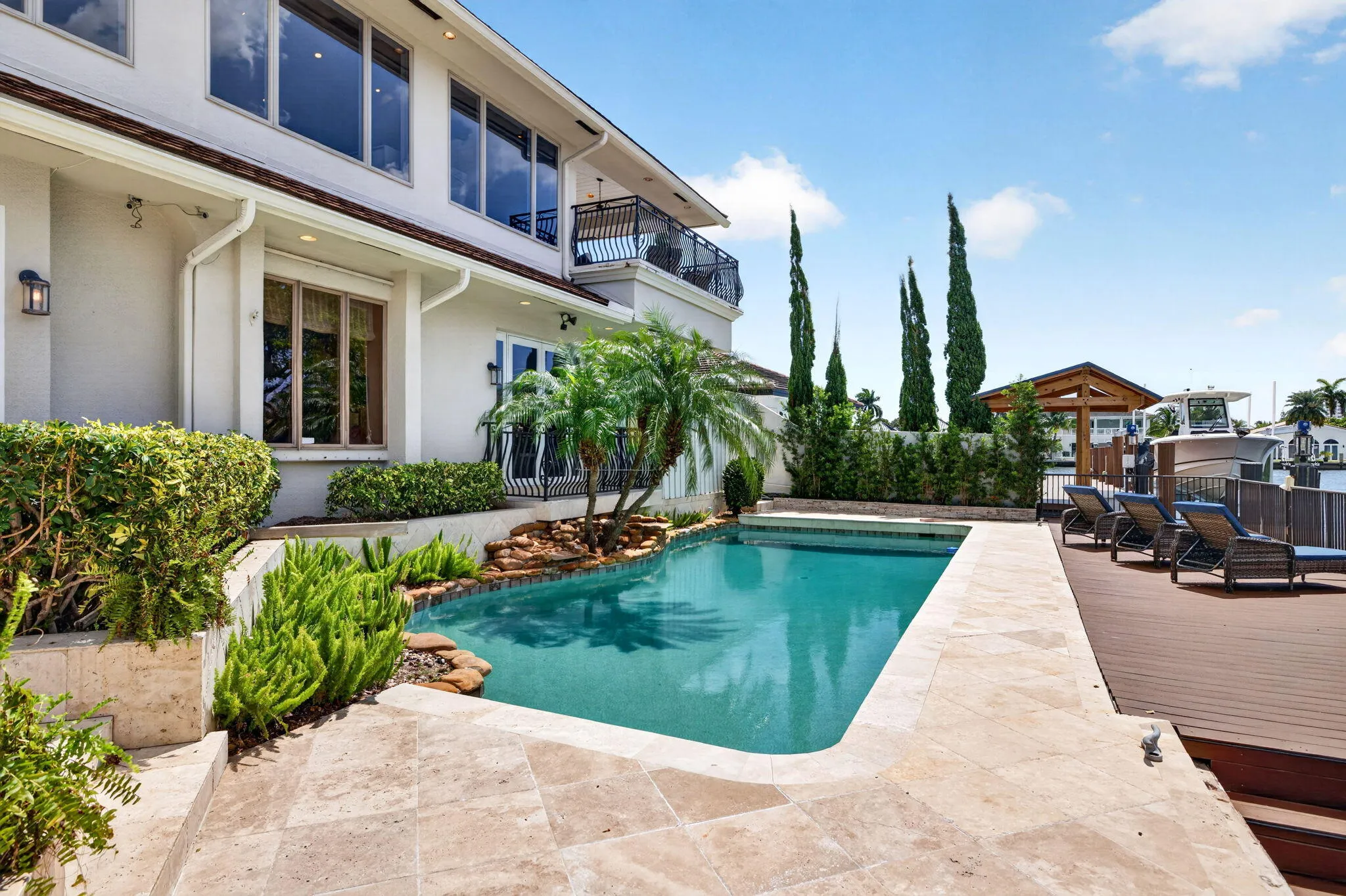 The pool deck showcases the rear elevation, outdoor living space, and direct connection to the water.