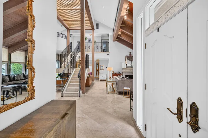 The foyer opens into a dramatic interior with soaring ceilings, architectural detail, and immediate sightlines into the main living areas.