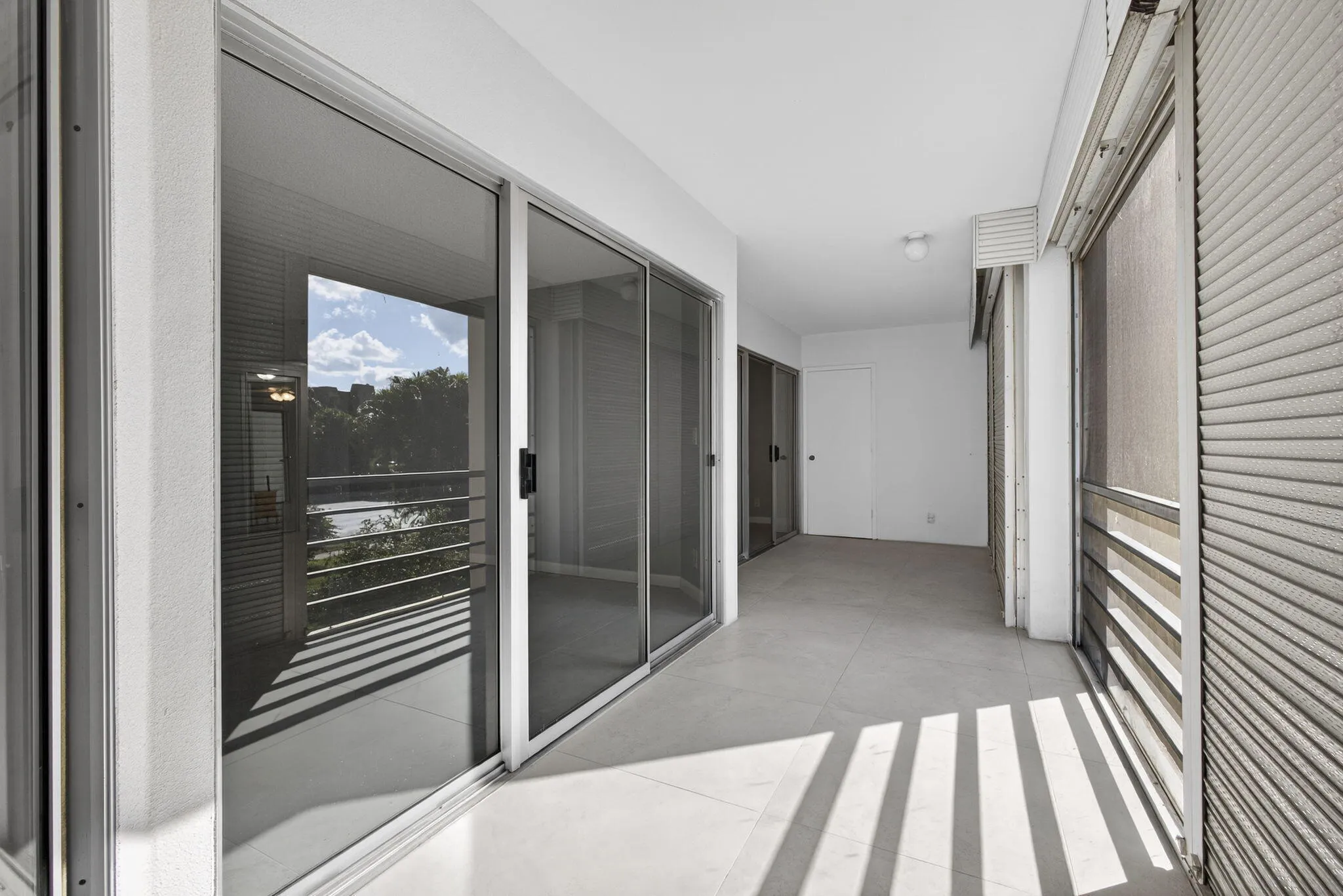View of balcony area from kitchen showing entry to living room (closest) and master bedroom far end