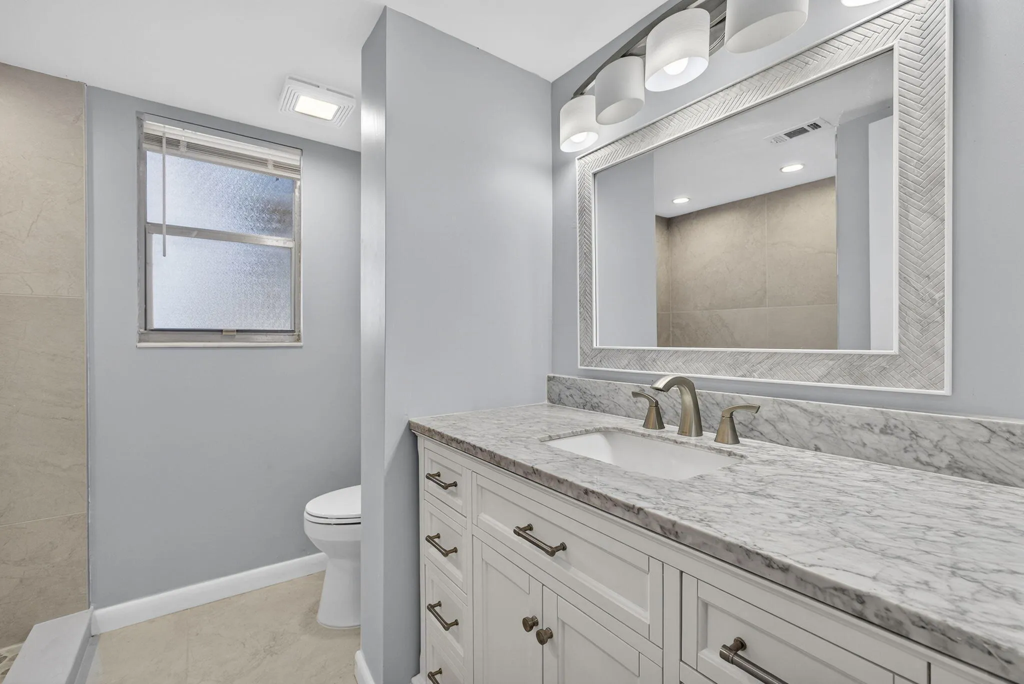 View of new vanity, mirror, lighting, and toilet in mast bathroom