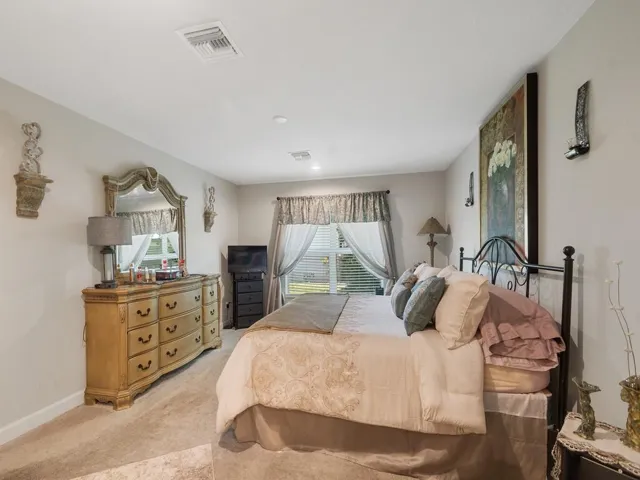 Spacious room featuring neutral carpeting, light-toned walls, and a large window with blinds and drapes