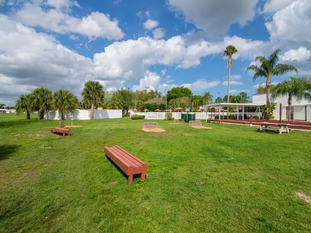Bocce ball court with covered seating, flanked by manicured green spaces and mature palm trees