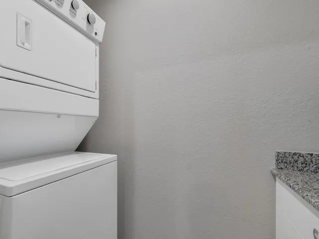 White stackable laundry appliances with a speckled countertop