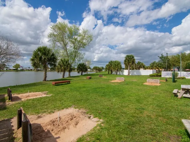 Bocce ball court with covered seating, flanked by manicured green spaces and mature palm trees