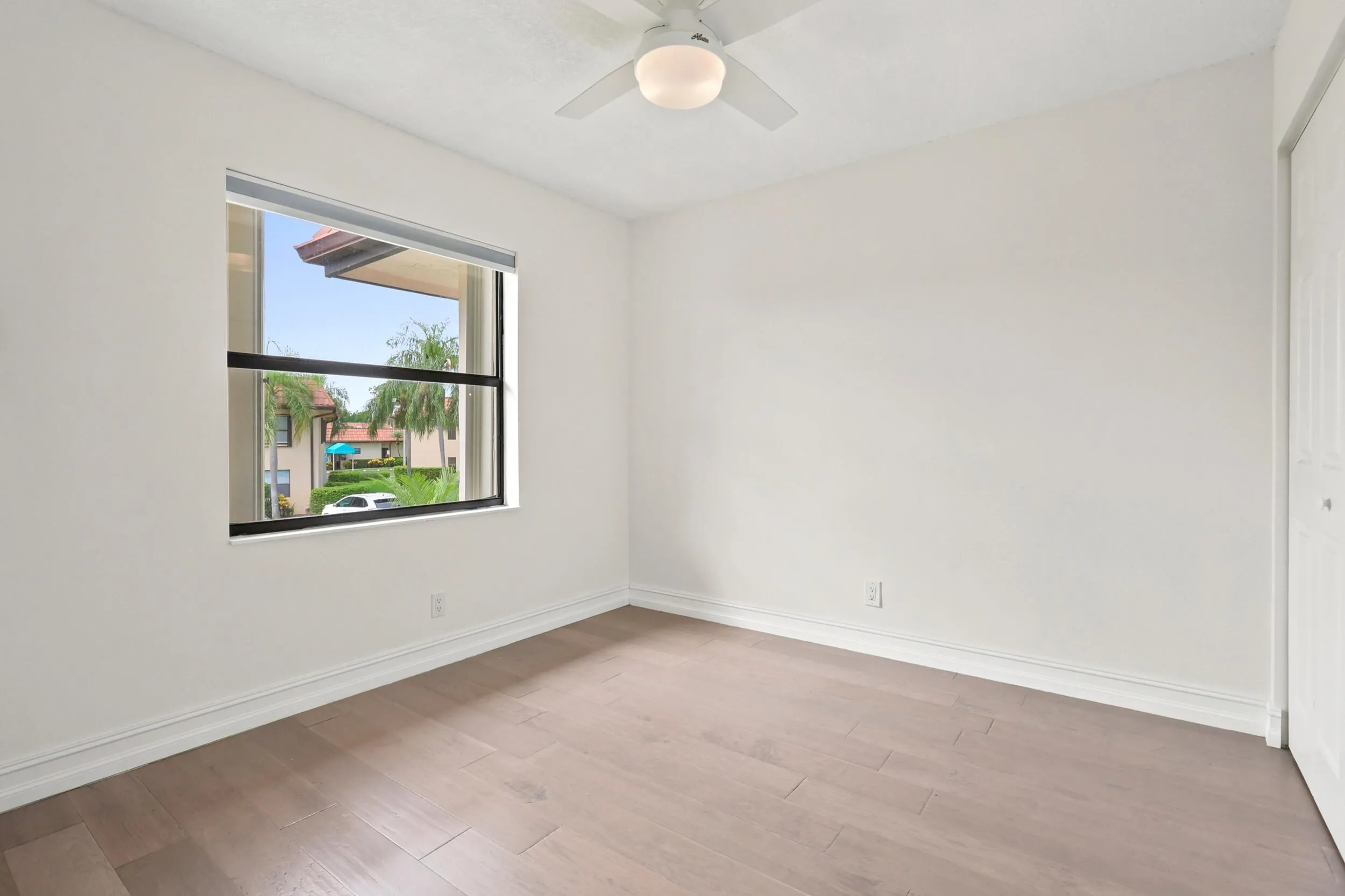 Bright and comfortable, the guest bedroom features updated flooring, generous closet space, and a large window that brings in plenty of natural light while overlooking the community's beautifully maintained grounds. The versatile layout is ideal for guests, a home office, or additional living space, offering both comfort and flexibility.
