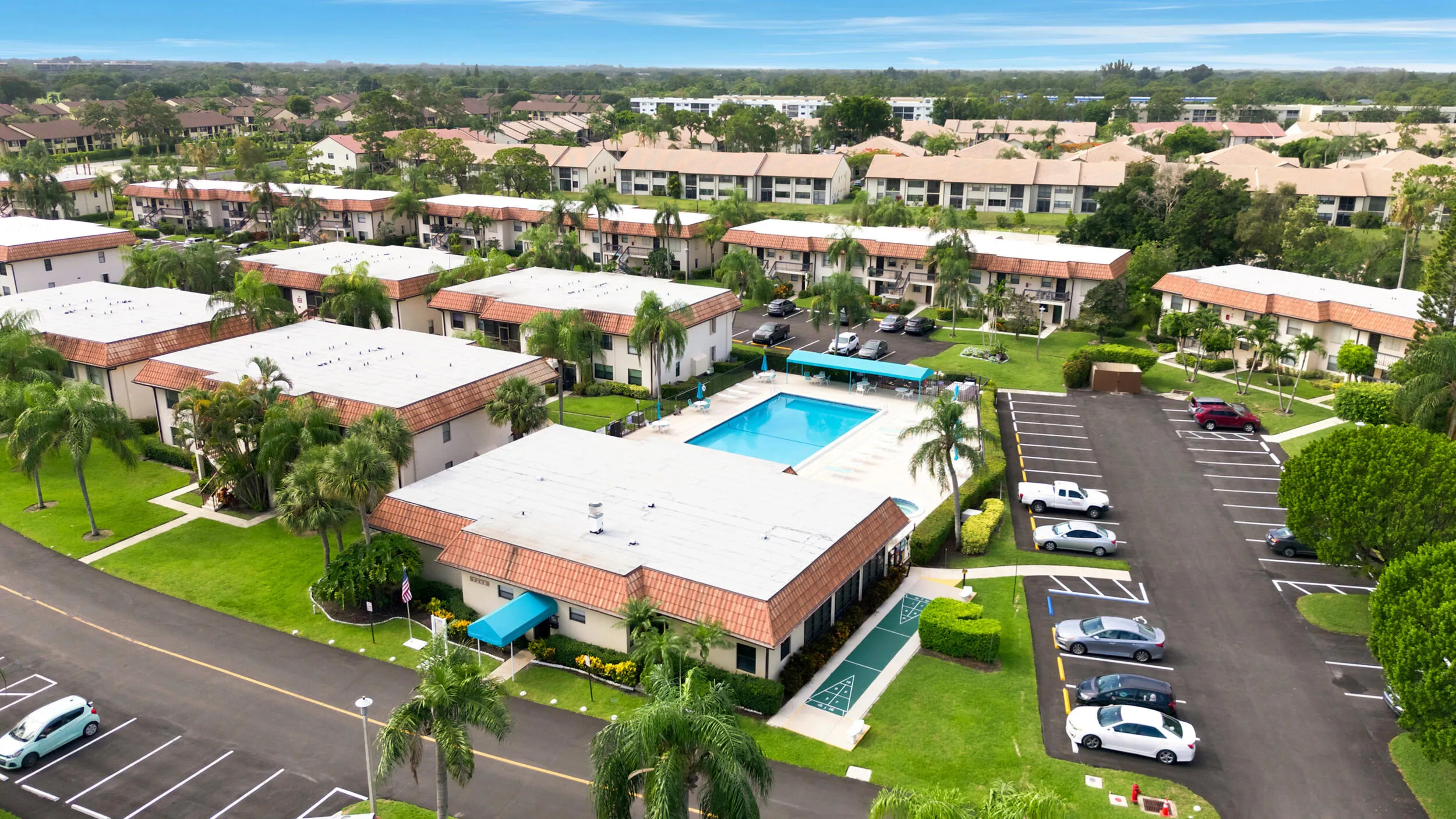Enjoy a bird’s-eye perspective of this well-maintained community, showcasing the building's convenient location, abundant parking, mature tropical landscaping, and beautifully maintained grounds. Positioned within a peaceful residential setting, the property offers easy access to nearby shopping, dining, golf courses, parks, and major commuter routes while providing a tranquil place to call home.