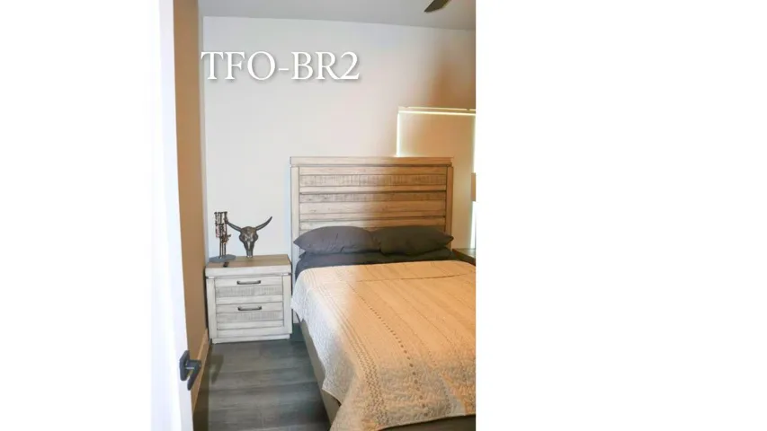 Located at the end of the hallway, this guest bedroom offers a queen-size bed, remote-controlled blackout blinds, and a quiet retreat for family or visitors. Wilton Manors home for sale, heated saltwater pool, smart home, vacation rental, South Florida living, move-in ready home, pool home, luxury primary suite, chef's kitchen, energy-efficient home.