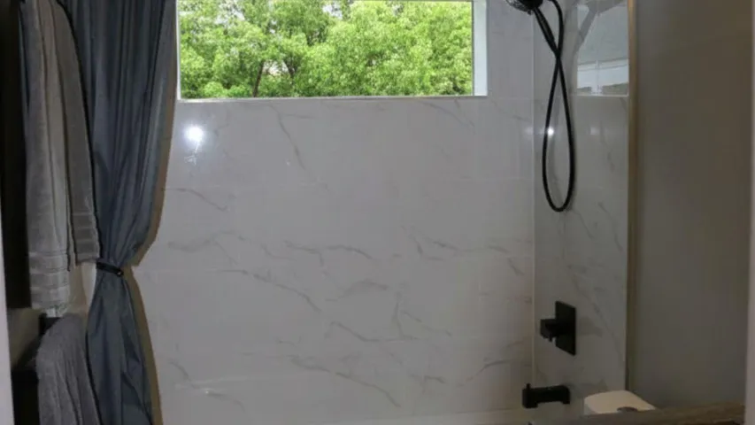 MAIN BATHROOM SHOWERUpdated main bathroom shower showcases modern finishes and a clean contemporary design. Wilton Manors home for sale, heated saltwater pool, smart home, vacation rental, South Florida living, move-in ready home, pool home, luxury primary suite, chef's kitchen, energy-efficient home.