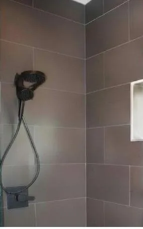 PRIMARY BATHROOM SHOWERSpa-inspired primary bathroom features dual shower heads and an overhead rainfall shower for a luxurious daily experience. Wilton Manors home for sale, heated saltwater pool, smart home, vacation rental, South Florida living, move-in ready home, pool home, luxury primary suite, chef's kitchen, energy-efficient home.