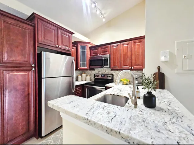 KITCHEN HAS CUSTOM CABINETRY, STAINLESS STEEL APPLIANCES AND GRANITE COUNTERTOPS