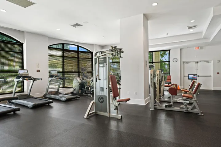 Fully equipped fitness center with treadmills, cardio equipment, strength machines, and large windows.
