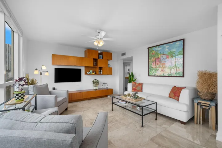 Refined living area with marble flooring, a custom built-in media wall, and a bright corner setting.