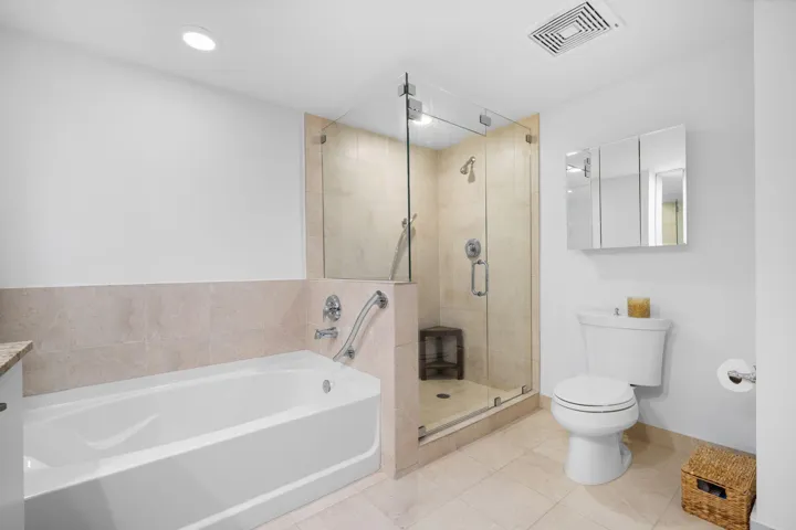 Spa-like primary bathroom featuring a soaking tub and separate glass-enclosed walk-in shower.